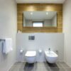 Lichte badkamer met hangtoilet, bidet, inbouwreservoir en warme houtlook accentwand met spiegel — badkamerrenovatie Niscon Group Noord-Brabant