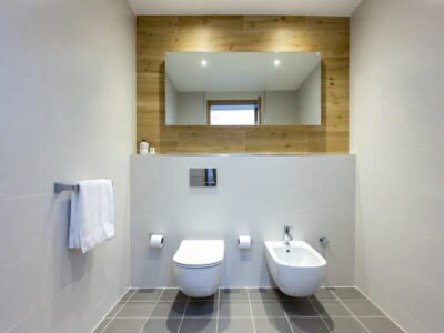 Lichte badkamer met hangtoilet, bidet, inbouwreservoir en warme houtlook accentwand met spiegel — badkamerrenovatie Niscon Group Noord-Brabant