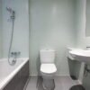 Compacte badkamer met ligbad, staand toilet, wastafel, lichte wandtegels en donkere vloertegels — badkamerrenovatie Niscon Group Noord-Brabant
