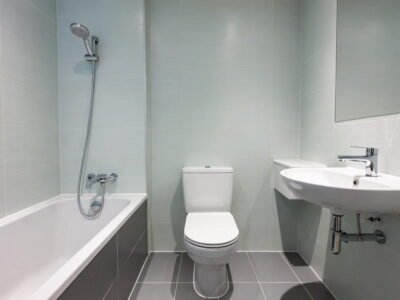 Compacte badkamer met ligbad, staand toilet, wastafel, lichte wandtegels en donkere vloertegels — badkamerrenovatie Niscon Group Noord-Brabant