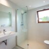 Lichte beige getegelde badkamer met glazen inloopdouche, zwevende wastafel, hangtoilet en grote spiegel — badkamerrenovatie Niscon Group Noord-Brabant