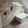 Luxe badkamer met marmerlook grootformaat tegels, inbouwnis en vrijstaand bad — badkamerrenovatie Niscon Group Noord-Brabant