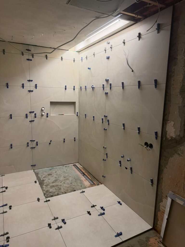 Badkamer in de ruwbouwfase met zichtbaar leidingwerk in het plafond en tegelclips op de wand — Niscon Group Noord-Brabant