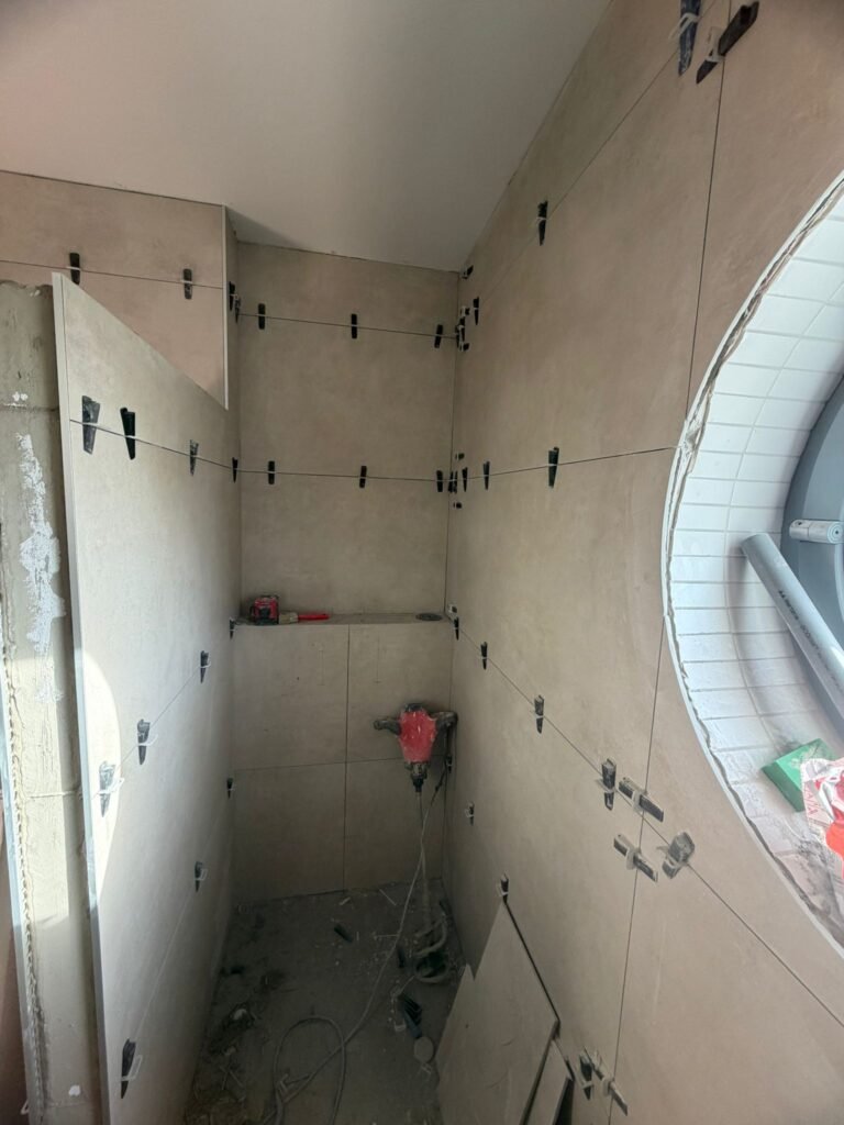 Eerste rijen wandtegels met levelclips tijdens het tegelzetten in een badkamerrenovatie — Niscon Group Noord-Brabant
