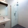 Witte badkamer met glazen inloopdouche, regendouche, zwevende wastafel en spiegelkast met donkere mozaïek douchevloer — badkamerrenovatie Niscon Group Noord-Brabant